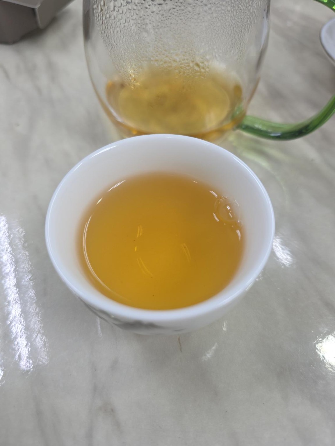 Deeper golden-yellow Gong Mei liquor in infusion 2, with a glass pitcher behind the cup